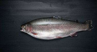 Siyah ahşap bir masada taze çiğ somon balığı. Balıklardan, deniz ürünlerinden, üst manzaradan, düz yataktan oluşan yaratıcı bir düzen.