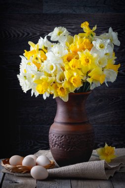  Taze bahar, parlak sarı nergisler, koyu arkaplanda kil bir vazoda çiçekler.. 