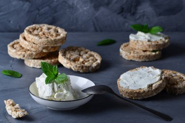 Krem peyniri ve tüm tahıl gevrekleri gri bir masada..