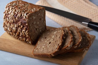 Kesme tahtasında dilimlenmiş çavdar ekmeği. Tohumlu tam tahıllı çavdar ekmeği.