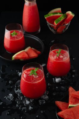 Bardaklarda taze karpuz suyu ve karpuz parçaları.