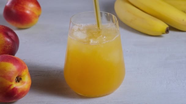 Χυμός φρούτων σε ποτήρι. Ανακατεύοντας χυμό φρούτων με πάγο για υγιεινό ποτό — Αρχείο Βίντεο