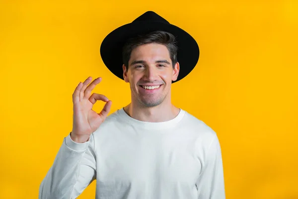 Homem mostrando sinal de polegar sobre fundo amarelo. Um jovem positivo sorri para a câmara. Vencedor. Sucesso. Linguagem corporal. — Fotografia de Stock