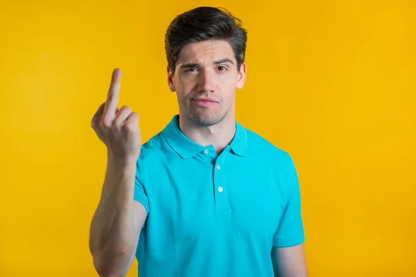 Молодий красивий чоловік на жовтому тлі, що показує середній палець жест хуй. Вираз негативний, агресія, провокація . — стокове фото