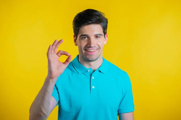 Mann zeigt Daumen-hoch-Zeichen über gelbem Hintergrund. Positiver junger Kerl lächelt in die Kamera. Sieger. Mit Erfolg. Körpersprache. — Stockfoto