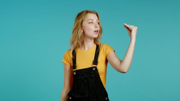 Cute girl showing bla-bla-bla gesture with hands and rolling eyes isolated on blue background. Empty promises, blah concept. Lier. — Stock Video