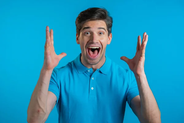 Der Mensch zeigt Verblüffung, zeigt WOW Entzücken Gesichtsausdruck. Überrascht aufgeregt fröhlicher Kerl. Schöne männliche schockiert Modell auf blauem Hintergrund. — Stockfoto