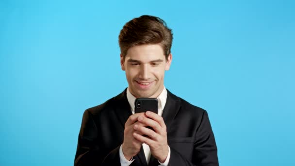 Jóképű üzletember kap boldog értesítést a mobilján. A fickó magán kívül van a meglepetéstől és az örömtől. Győzött és örül. Technológia, siker, győzelem, boldogság koncepció. — Stock videók