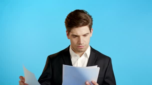 Jefe empresario serio aislado en el estudio de fondo azul. Joven empleado de oficina con chaqueta de traje comprobando documentos, informes — Vídeos de Stock