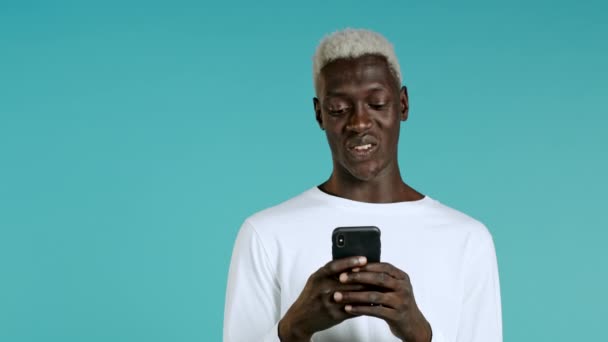 Bel homme noir reçoit une notification heureuse sur le téléphone mobile. Guy est hors de lui avec surprise et joie. Il a gagné et se réjouit. Technologie, succès, victoire, concept de bonheur. — Video