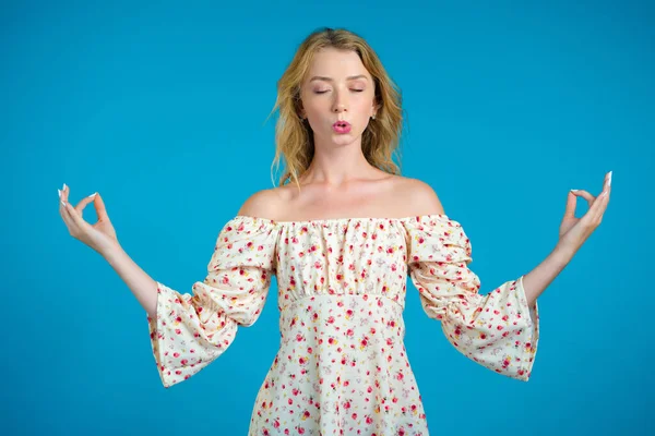 Sakin bir kadın dinleniyor, meditasyon yapıyor. Kız sakinleşiyor, derin derin nefes alıyor. Mavi stüdyo arka planında.