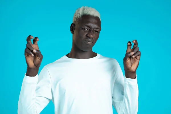 Hombre africano con el pelo blanco mostrando con las manos y dos dedos como el gesto de citas, doblar los dedos aislados sobre fondo azul. Concepto muy divertido, irónico y sarcástico. — Foto de Stock