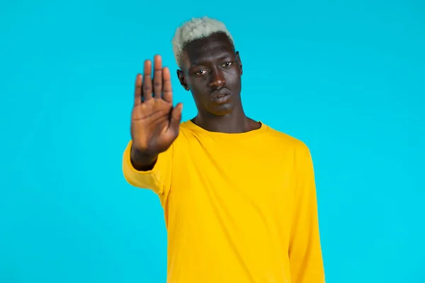 Retrato de un hombre afroamericano serio que muestra un gesto de rechazo por señal de stop palm. Tipo aislado sobre fondo azul. — Foto de Stock