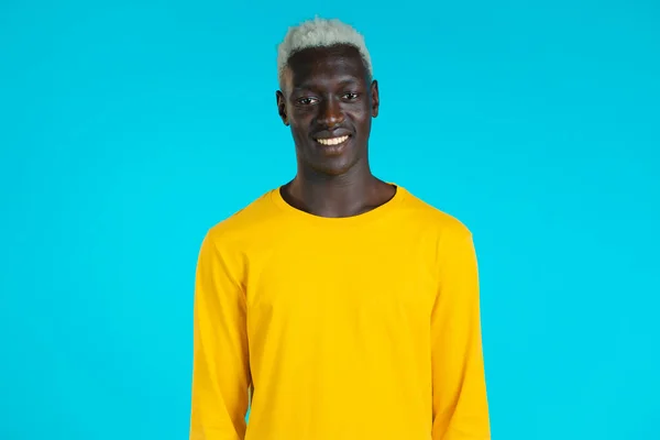 黄色のカメラを探してアフリカ系アメリカ人ハンサムな男の笑顔の肖像画。男でスタジオで明るい青の背景. — ストック写真