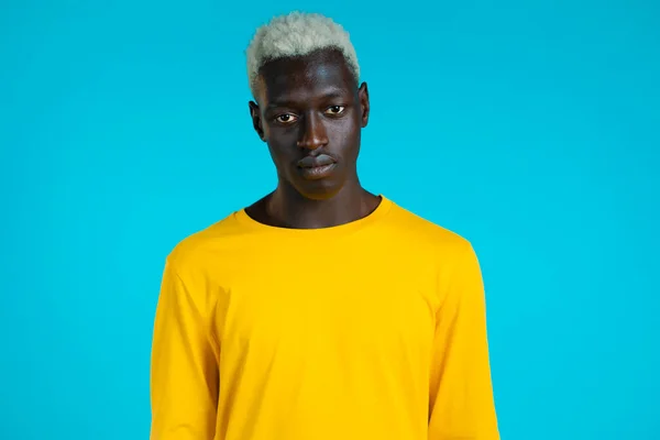 Retrato de um homem afro-americano bonito a olhar para a câmara. Cara em estúdio em fundo azul brilhante. — Fotografia de Stock