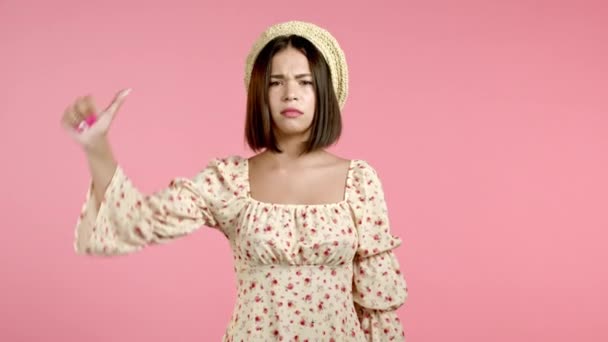 Νεαρή Ασιάτισσα στέκεται σε ροζ φόντο στούντιο εκφράζοντας δυσαρέσκεια και δείχνοντας τον αντίχειρα προς τα κάτω χειρονομία στην κάμερα. Πορτρέτο της γυναίκας με το σημάδι της αντιπάθειας. — Αρχείο Βίντεο