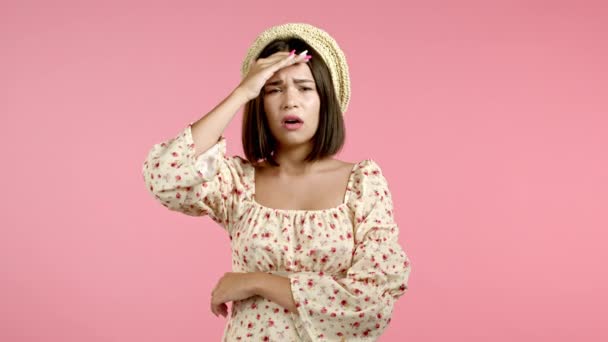 Mujer joven con dolor de cabeza, retrato de estudio. Chica poniendo las manos en la cabeza, aislado sobre fondo rosa. Concepto de problemas, medicina, enfermedad — Vídeos de Stock