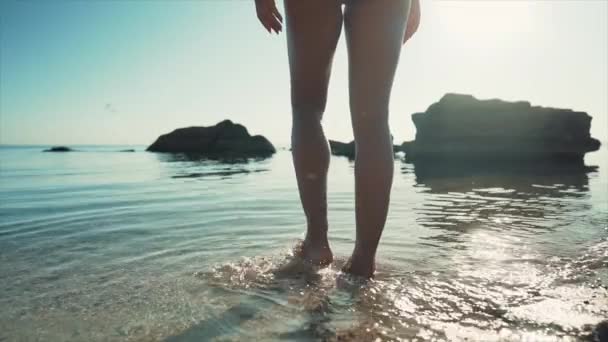 Неузнаваемая женщина, идущая в морскую воду. Девушка с худым сексуальным телом на тропическом отдыхе, песчаный пляж с камнями. Элитное направление. Путешествие, природа, летняя концепция. Медленное движение. — стоковое видео