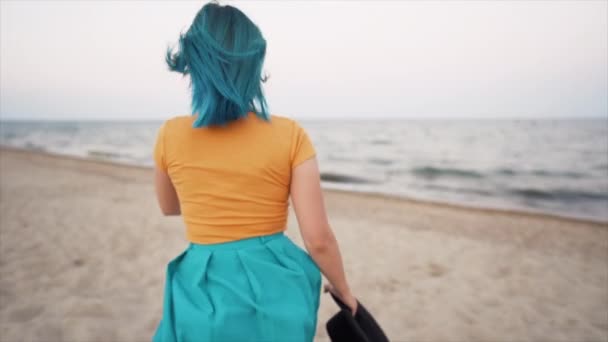 Hezká žena s barvenými modrými vlasy běží v blízkosti moře nebo oceánu, těší svobodu během letních prázdnin, cestování. Venku je krásná šťastná dívka. Zpomalený pohyb. — Stock video