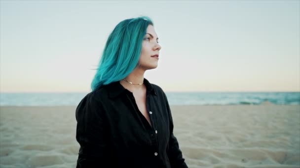 Atrakcyjna unikalna kobieta z ciemnym morskim błękitem lub turkusową fryzurą na tle morza. Portret hipsterki z niezwykłymi włosami cieszącej się latem w samotności. — Wideo stockowe
