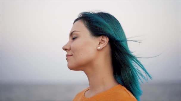 Atractiva mujer única con azul azulado o turquesa peinado teñido en el fondo de la playa de mar. Retrato de chica hipster con el pelo inusual disfrutando de verano solo. — Vídeos de Stock