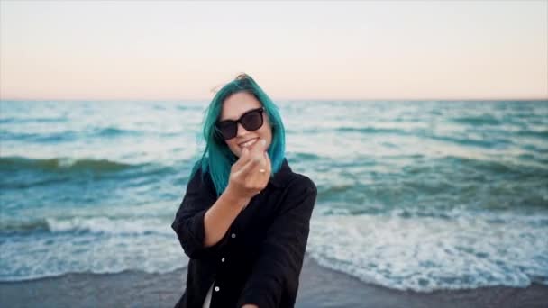 Mujer inusual con el pelo teñido de azul bailando, girando las manos sobre el fondo del mar. Feminidad, vacaciones, vitalidad, concepto de vida saludable. Chica divirtiéndose, reír. — Vídeos de Stock