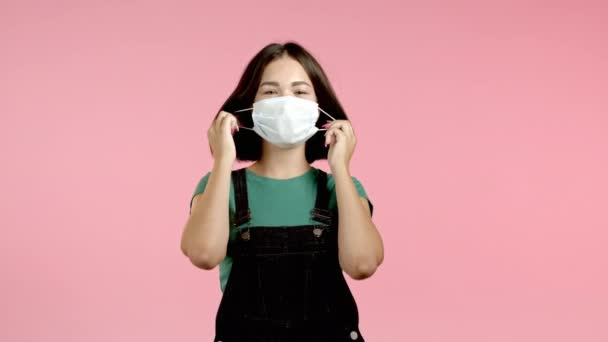 Donna soddisfatta rimosso maschera protettiva come simbolo di pandemia, fine epidemia. Rosa studio sfondo. — Video Stock