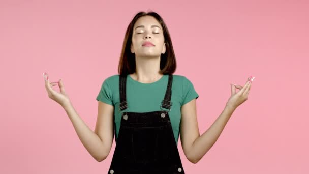 Femme calme aux cheveux bruns relaxant, méditant. Fille se calme, respire profondément avec mudra om sur fond de studio rose — Video