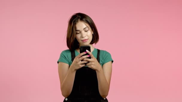 Jolie femme brune avec téléphone portable. Fille en utilisant un smartphone, surfer sur Internet, bavarder sur les réseaux sociaux. Concept technologique. — Video