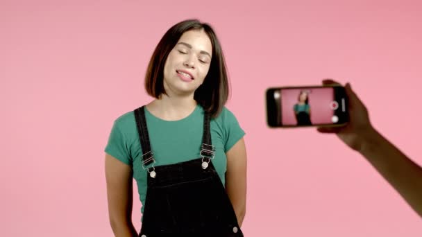 Leende mode bloggare kvinna att göra online ny video blogg, vlog, med sin smartphone på rosa bakgrund. Influencer talar till kameran under konferenssamtal rekord. — Stockvideo