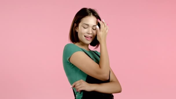 Jonge vrouw met bob kapsel op zoek naar camera, flirten. Een mooi modelmeisje demonstreert zichzelf. Roze studio achtergrond. — Stockvideo