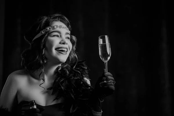 Vintage Art Deco styled woman dressed raises glass of champagne like toast, drinking wine on velours background. Roaring twenties, retro, party, fashion concept