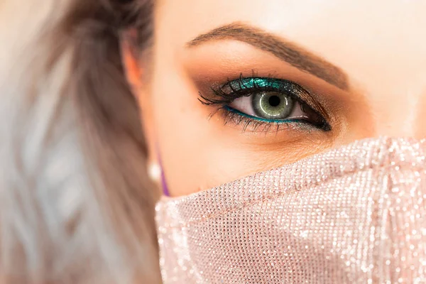 Frauengesicht in glitzernder Schutzmaske, tolles Make-up. Weibchen mit leuchtenden Schatten. Nachtleben, Nachtclub, Pandemie, Covid-19-Konzept. — Stockfoto