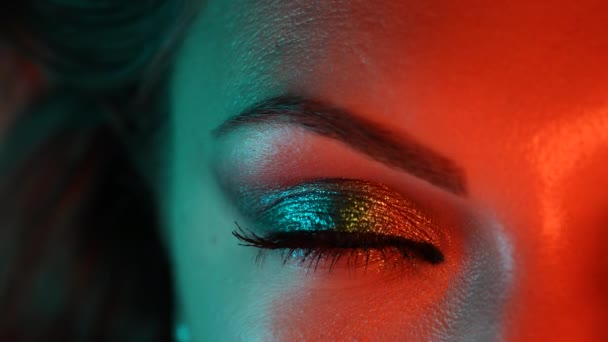 Vrouw gezicht, meisje flirt met gezichtsuitdrukkingen, beweegt een wenkbrauw. Neon licht. Vrouw met mooie make-up, glitter schaduwen. Schoonheid, cosmetica, nachtclub lifestyle concept. — Stockvideo