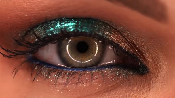 Extreme close-up van het menselijk oog iris. Vrouw met mooie make-up, glitter schaduwen. Womens groen oog samentrekken. Schoonheid, cosmetica, vrouwelijk concept. — Stockvideo