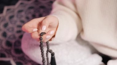 Kadın, elini yakar, Malas 'ı sayar. Mantra meditasyonları sırasında saymak için kullanılan lav boncukları..