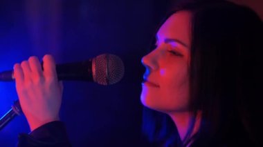 Genç ve güzel bir kadın konser sırasında mikrofonda şarkı söylüyor..