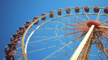 Mavi gökyüzünde bir dönme dolap görünüyor. Lunaparktaki dönme dolap.