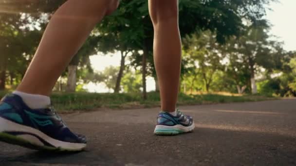 Une fille qui marche dans le parc le matin. Jeune femme brune séduisante et sportive qui court sur une route vide le matin. Au ralenti. Seulement les jambes. — Video