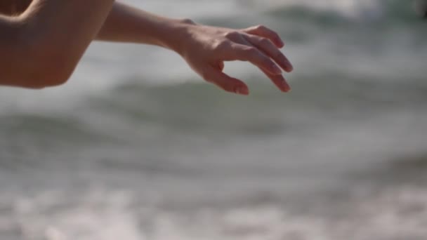 Dansçı kızın elleri deniz dalgalarının arka planına doğru yumuşak hareketler yapıyor. Ağır çekim. Balerin suda bale yapıyor.. — Stok video