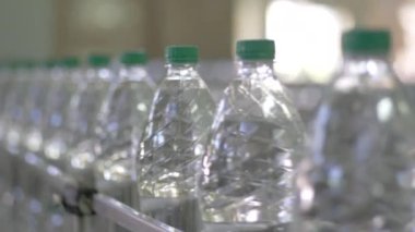 Plastik şişedeki maden suyunu şişelemek için otomatik taşıma hattı. PET şişe suyu için sıra. Su fabrikasındaki saf kaynak suyunu şişelere dolduruyor. Seçici odak.