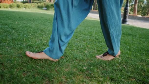 Jeune femme marchant pour s'entraîner le matin. Fille en pantalon bleu et chaussettes tricotées noires. Concentre-toi sur les jambes. Herbe verte, parc. Jours d'été. Mouvement lent. — Video