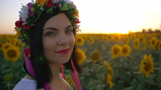 Retrato de mulher jovem e bonita no campo de girassol no pôr do sol. Senhora de coroa de flores. Movimento lento. Liberdade e conceito despreocupado. — Vídeo de Stock