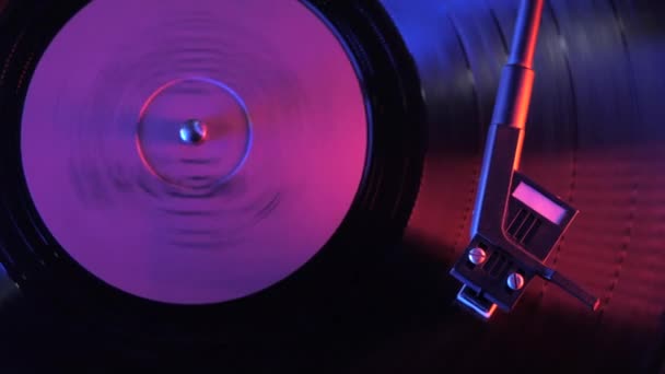 Een retro-stijl draaiende vinyl platenspeler. Vintage video van oude grammofoon, van dichtbij aan het spelen. 4k. Tijd verstrijkt. Mooie kleurrijke film. Neon violet ledlicht. — Stockvideo
