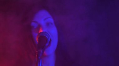Genç ve güzel bir kadın konser sırasında mikrofonda şarkı söylüyor..