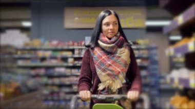 Süpermarketten alışveriş yapan müşteriler, alışveriş arabalı kadınlara odaklanırlar. Yavaş çekim.