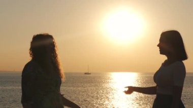 Güzel, genç ve çekici kadınlar konuşuyor ve gülümsüyor. Kızlar yazları birbirleriyle iletişim kuruyor ve deniz ya da okyanusun yanında duruyorlar. Yavaş çekim.