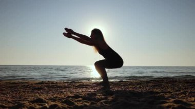Kum Denizi Sahili 'nde sabah yogası yapan güzel bir kadın. Surya Namaskar - Güneş selamları. Yavaş çekim.