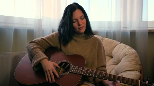 Schattig jong meisje spelen akoestische gitaar thuis — Stockvideo