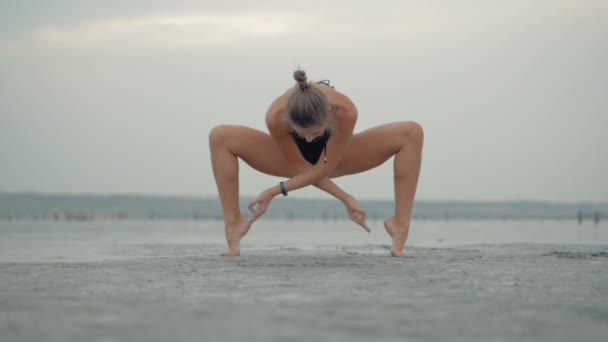 Concetto di esercizio di vita sana Giovane donna in forma sportiva che fa yoga Saluto al sole Surya Namaskar posa Hasta Uttanasana sulla spiaggia al tramonto. Rallentatore. — Video Stock
